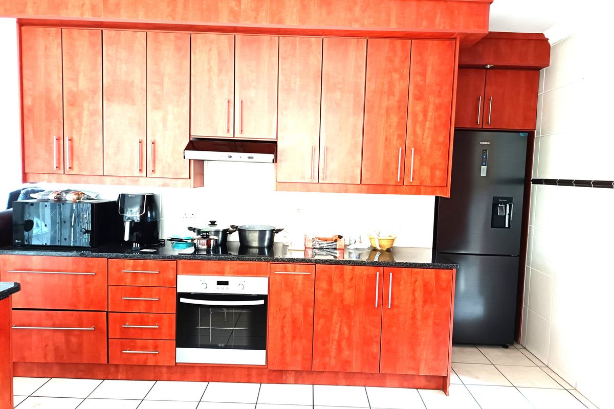 A functional kitchen featuring cherry-wood cabinetry, granite countertops, a built-in oven, extractor fan, and tiled flooring.