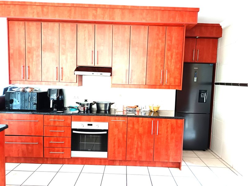 A functional kitchen featuring cherry-wood cabinetry, granite countertops, a built-in oven, extractor fan, and tiled flooring.