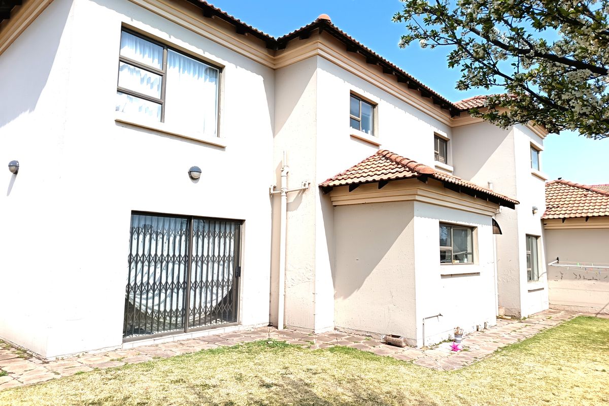 Rear view of a double-story residential house featuring tiled roofing, paved walkways, and security gates on sliding doors.