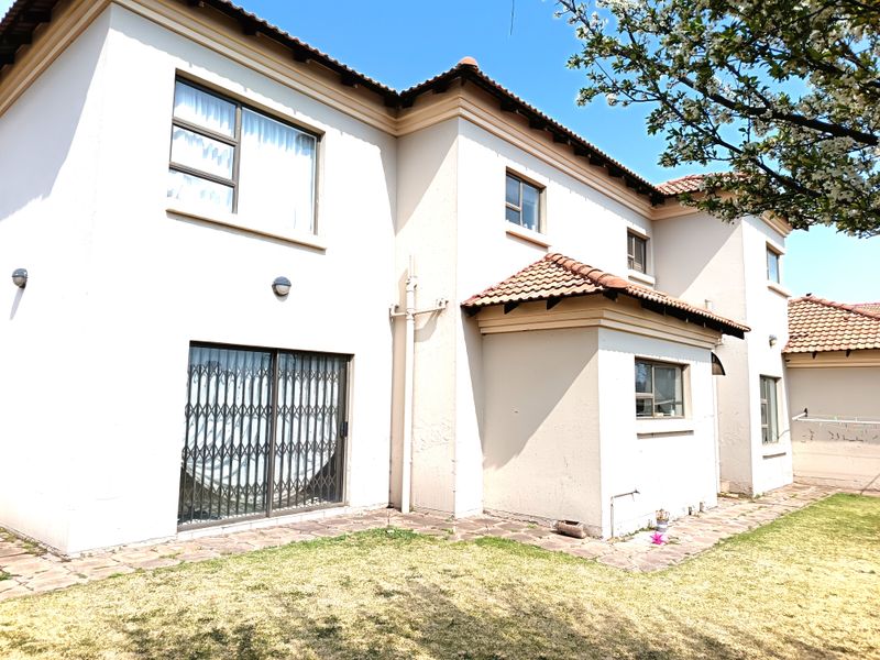 Rear view of a double-story residential house featuring tiled roofing, paved walkways, and security gates on sliding doors.