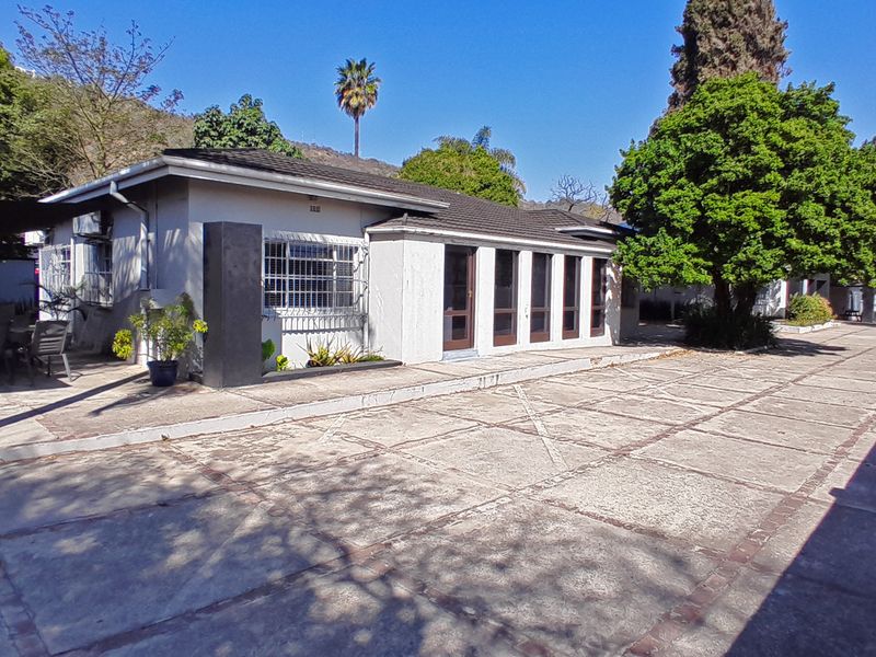 Rear exterior view of the house featuring a paved courtyard, tiled roof, and multiple sliding door access points.