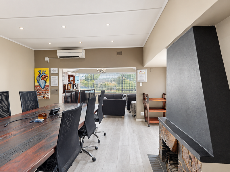 Spacious living area featuring a prominent stone fireplace, modern laminate flooring, and a split-system air conditioner, with an open-plan layout leading to adjacent space.