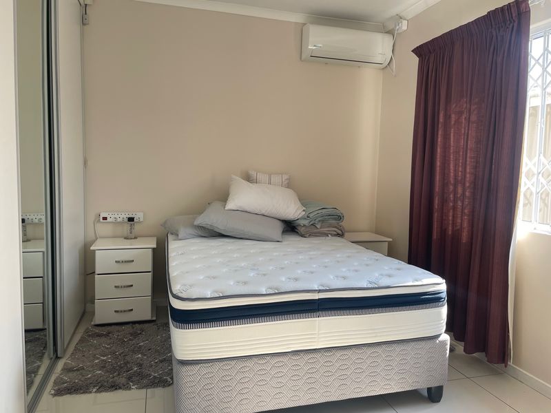 A functional bedroom featuring tiled flooring, a built-in wardrobe, and a wall-mounted split-system air conditioner for climate control.
