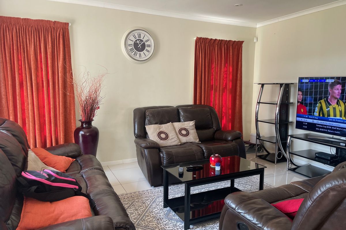 A comfortable living room featuring neutral wall tones, tiled flooring, and decorative cove cornicing, providing a functional space for relaxation.
