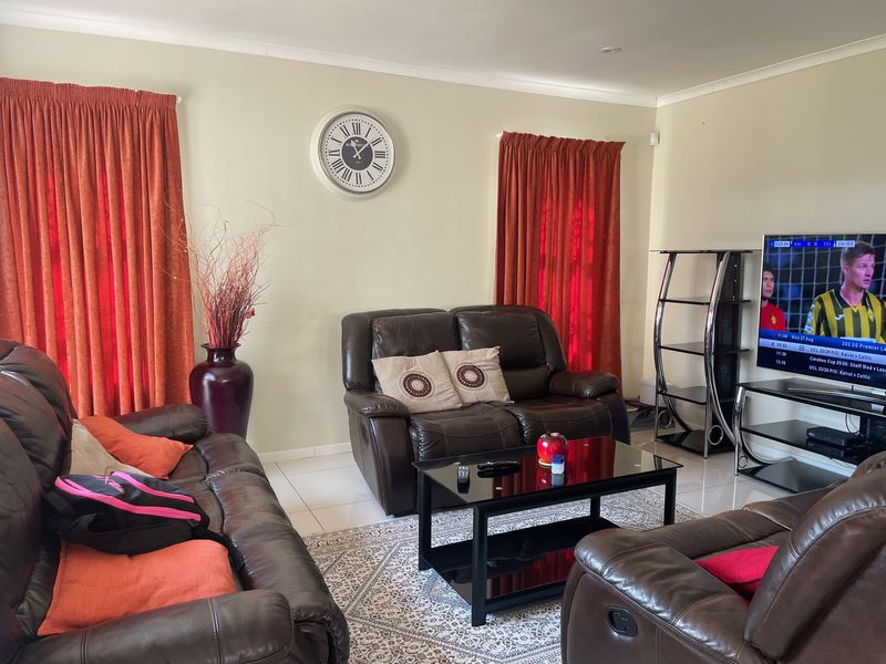 A comfortable living room featuring neutral wall tones, tiled flooring, and decorative cove cornicing, providing a functional space for relaxation.