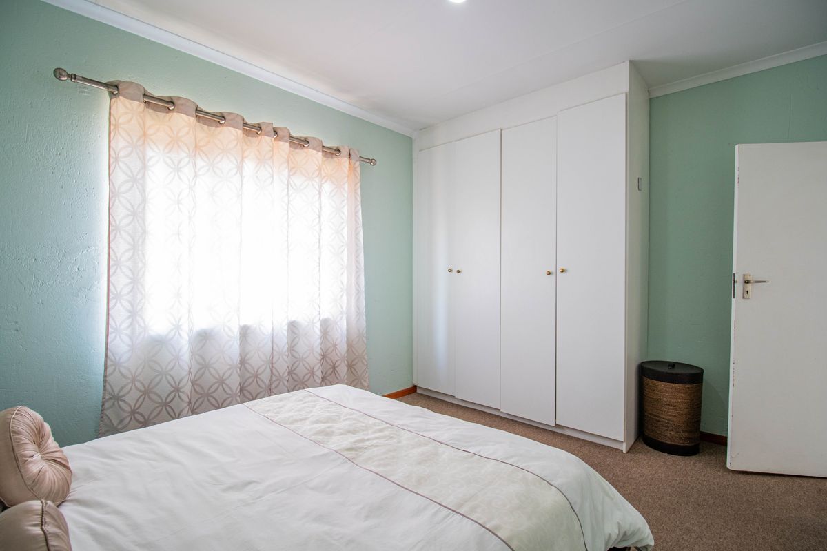 A bedroom featuring built-in cupboards, carpeted flooring, and a window with a curtain rod.