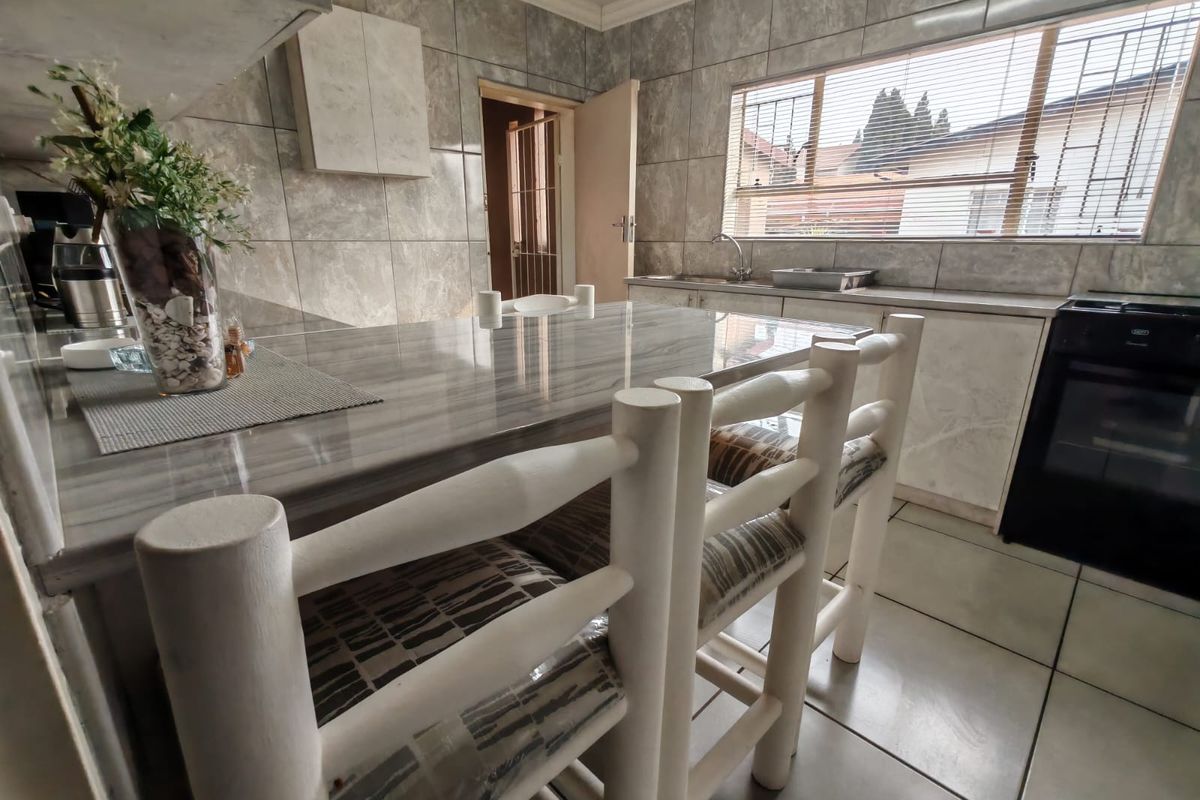 A functional kitchen featuring tiled walls, a breakfast counter, and built-in cabinetry with a view through the window.