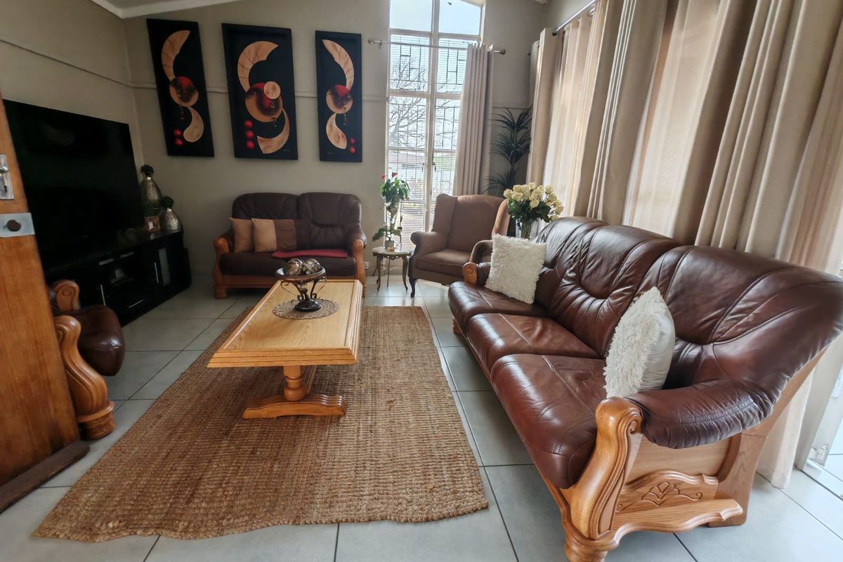 A spacious living room featuring large windows, tiled flooring, and high ceilings, providing a bright and comfortable area for relaxation.