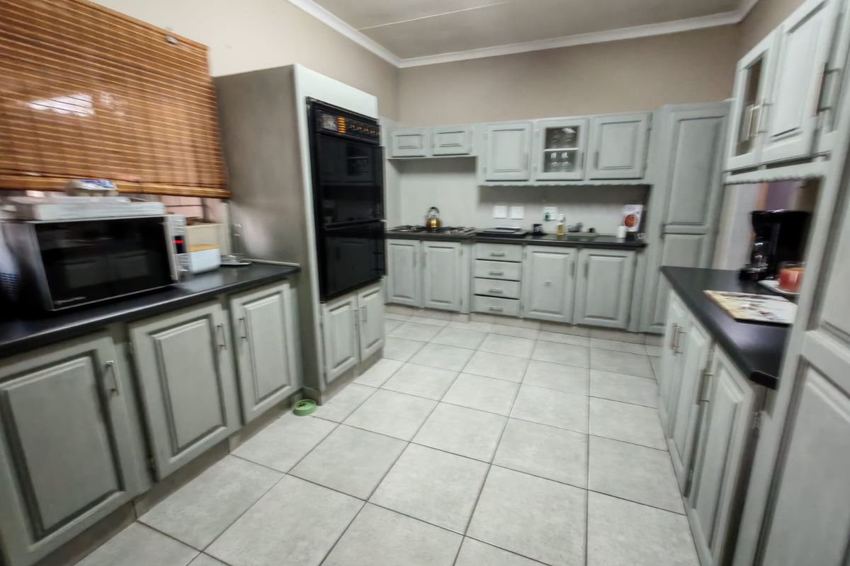 A functional kitchen featuring built-in cabinetry, a double oven, hob, and tiled flooring, offering a practical layout with potential for modern updates.