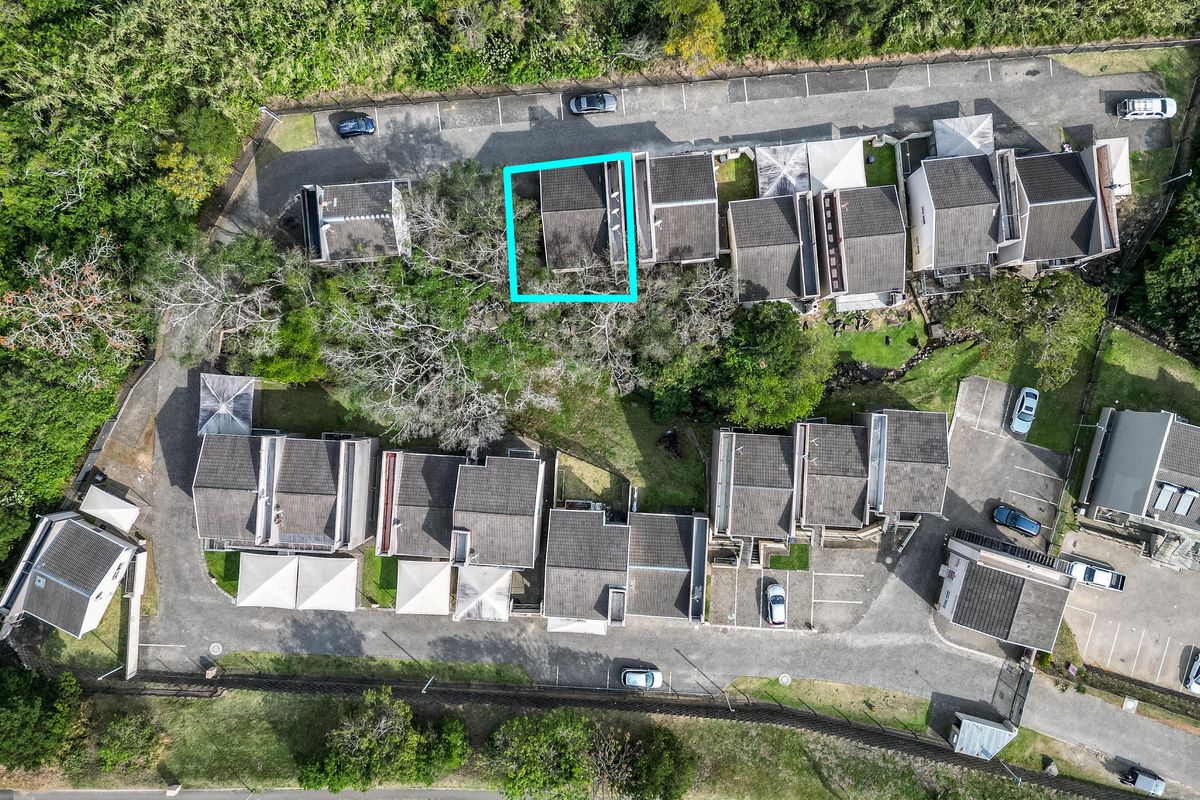 Aerial view of the apartment complex showing the unit location, roof structure, parking areas, and surrounding landscaped grounds.