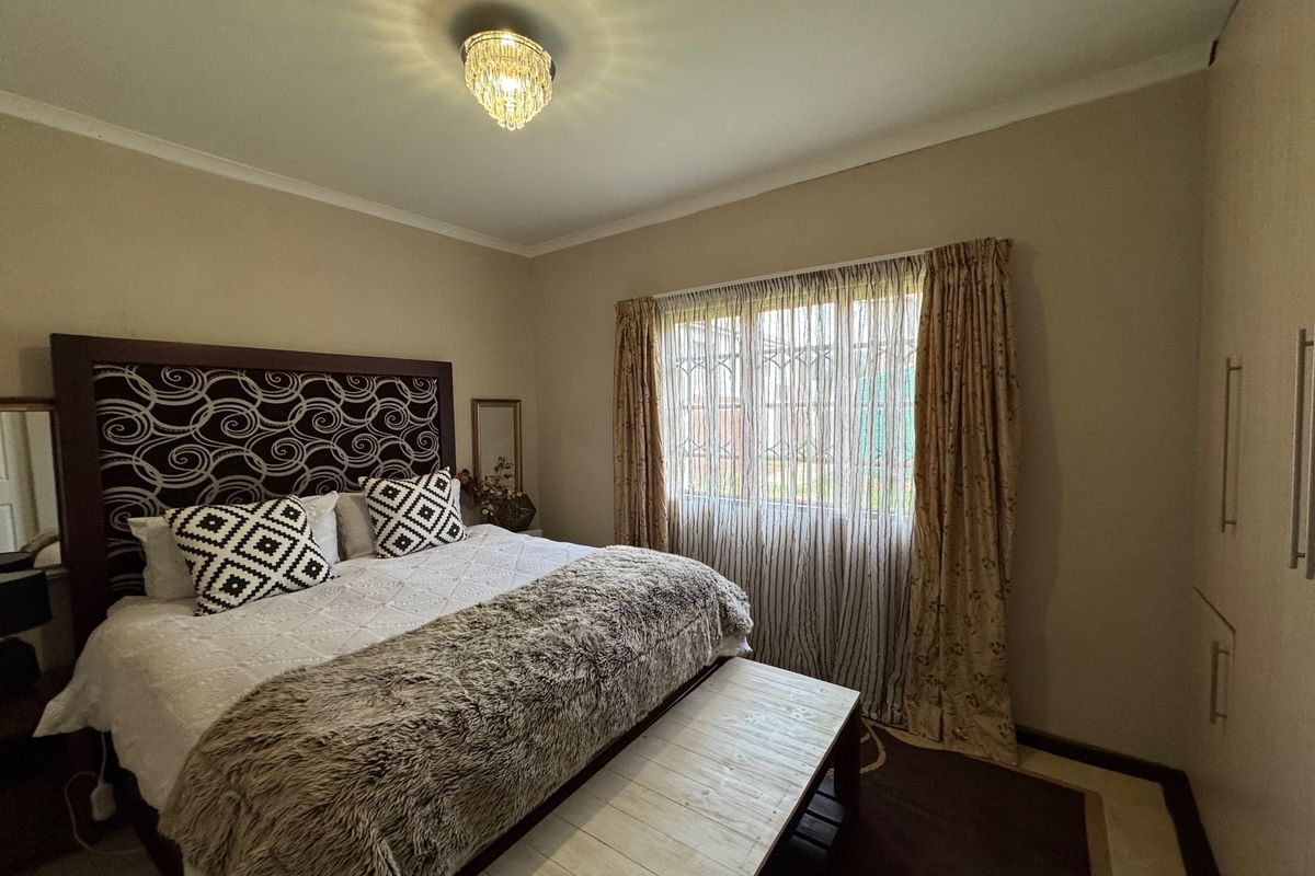 A well-maintained bedroom featuring built-in cupboards, neutral wall tones, and a security gate on the window for added peace of mind.