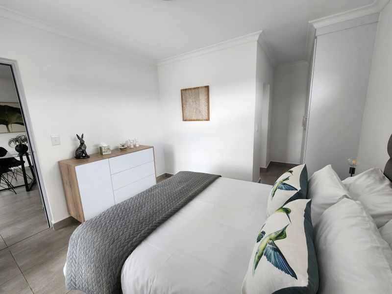 A well-maintained bedroom featuring neutral tiled flooring, built-in cupboards, and classic cove cornicing, offering a clean and functional living space.
