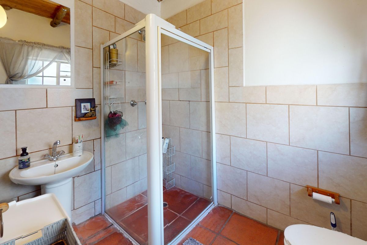 A functional bathroom featuring a pedestal basin, a corner shower enclosure with glass doors, and tiled wall and floor finishes.