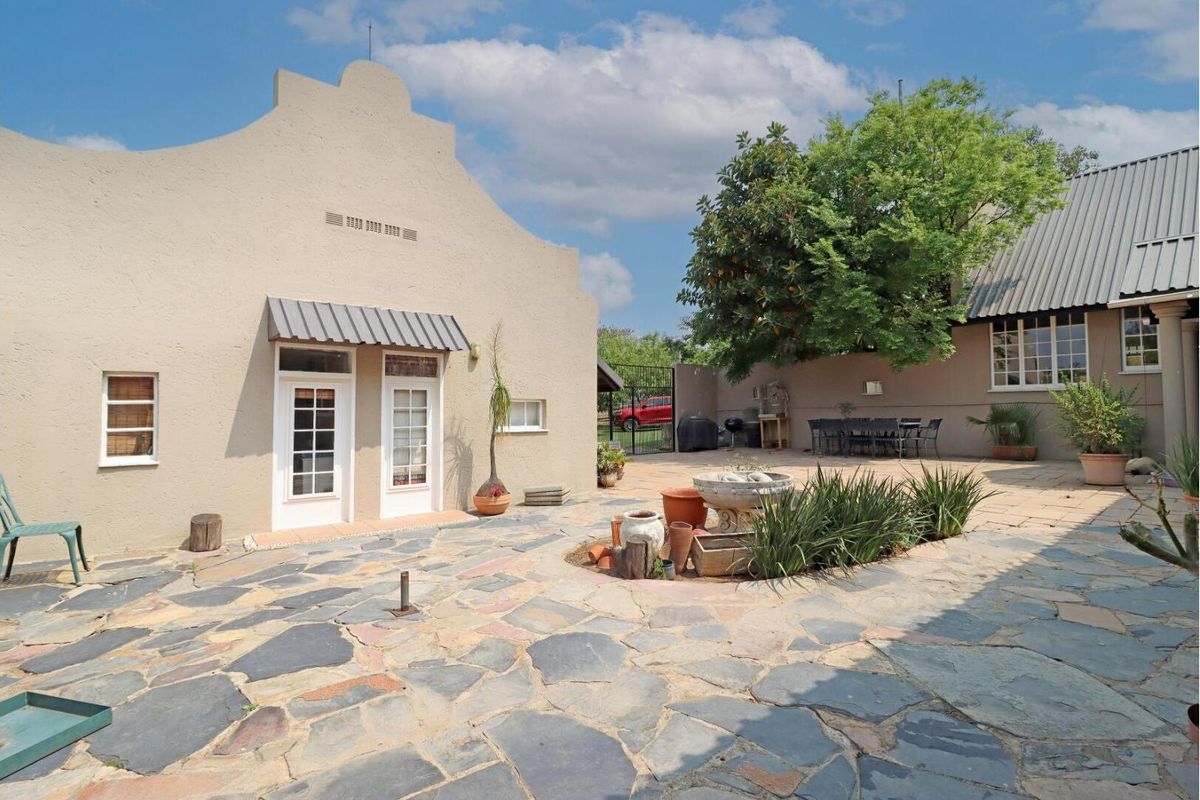 A spacious rear courtyard featuring natural slate paving, a gabled building facade, and a secure perimeter wall, ideal for outdoor entertaining.