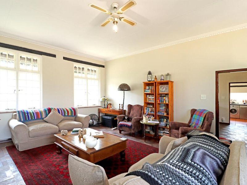 Spacious living room featuring classic parquet flooring, crown molding, and large multi-pane windows that provide ample natural light.