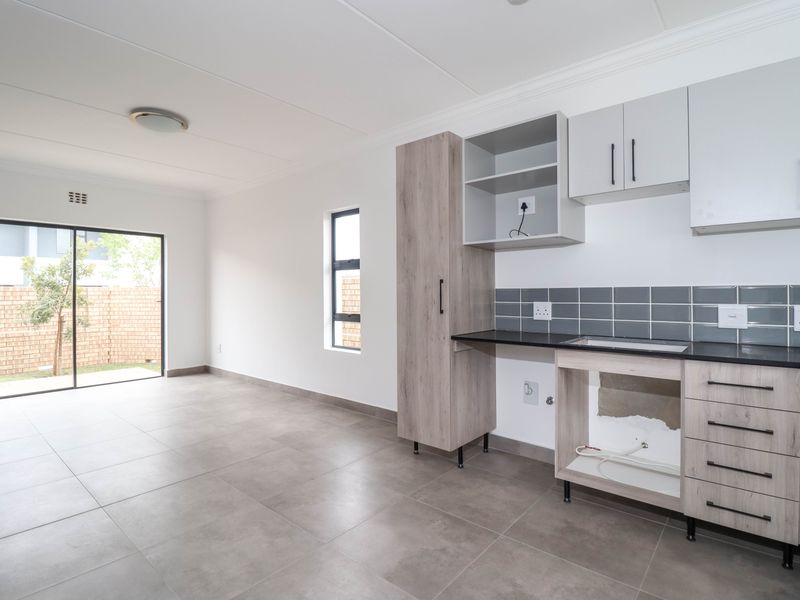 Open plan living and kitchen area featuring tiled floors, modern cabinetry, and a sliding door leading to the rear garden.
