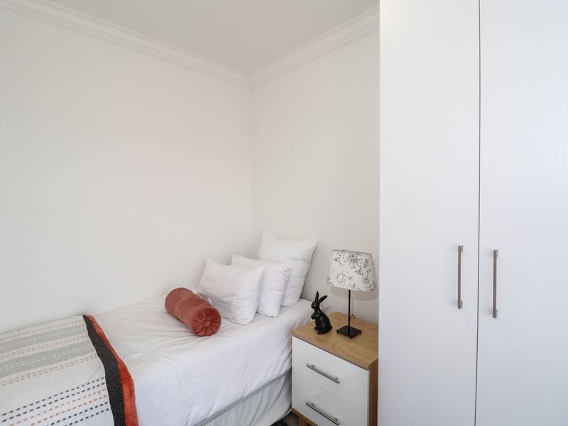 A clean and well-maintained bedroom featuring a built-in wardrobe and decorative cornice detailing.