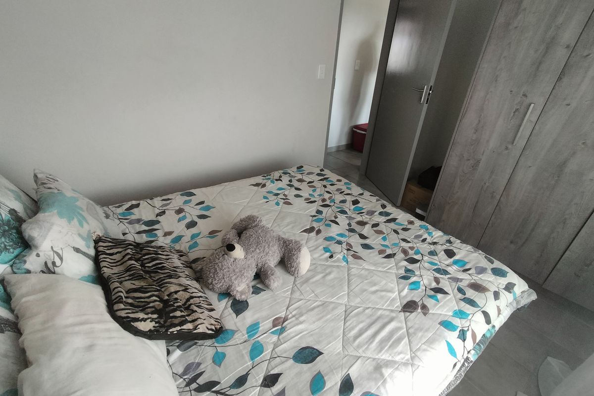 A well-maintained bedroom featuring modern laminate flooring and a built-in wardrobe with a neutral finish.
