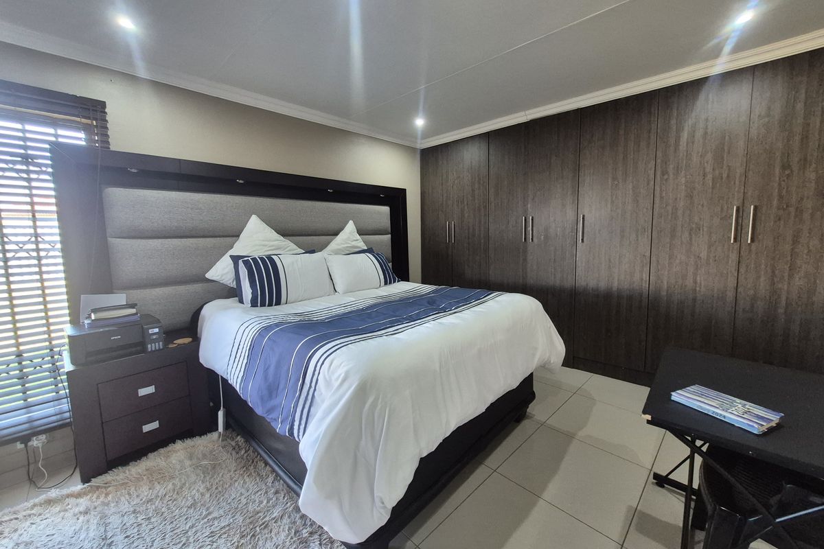 Spacious bedroom featuring extensive built-in dark wood cabinetry, tiled flooring, and recessed ceiling lighting.