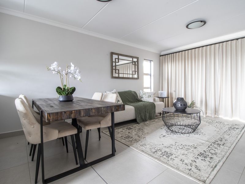 A bright and well-maintained open-plan living and dining area featuring neutral tiled flooring and modern ceiling fixtures.