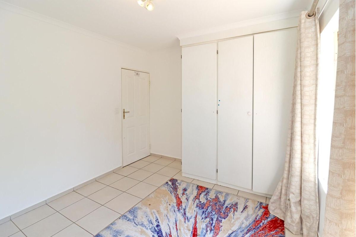 A bedroom featuring built-in cupboards and tiled flooring, providing a clean and functional living space.