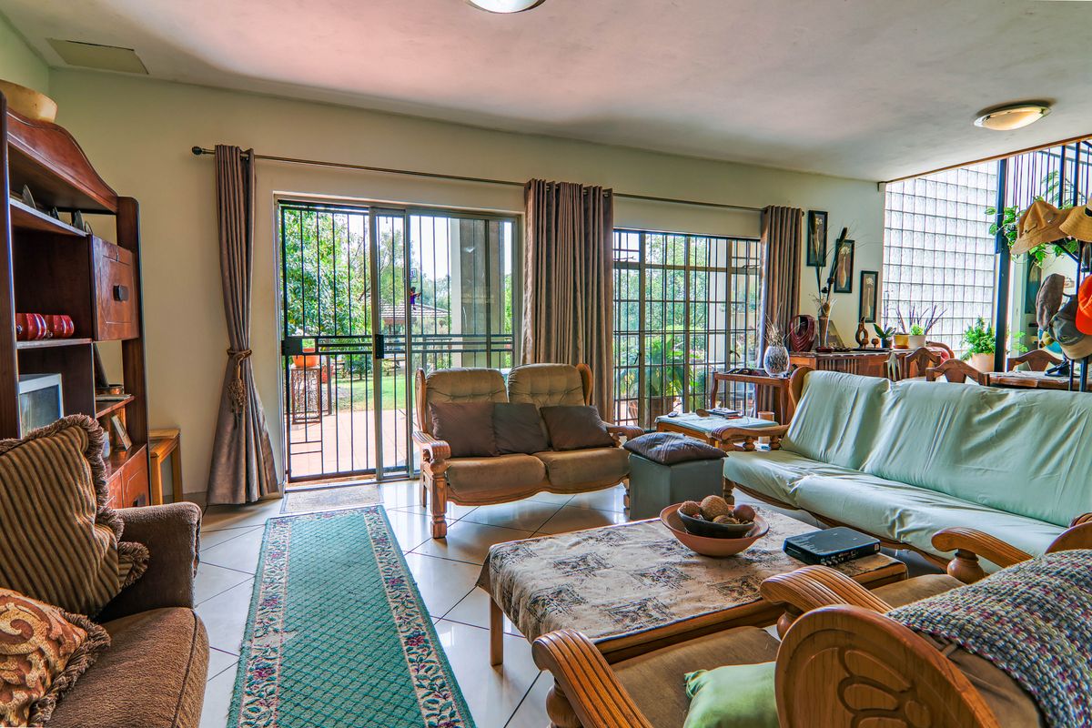 Spacious living room featuring tiled flooring, large sliding glass doors with security gates, and a unique glass block feature wall.