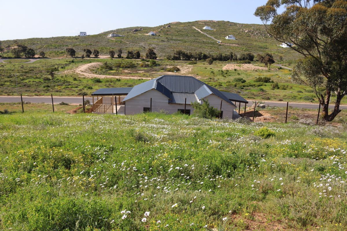 A view of the rear elevation of a residential property featuring a corrugated metal roof and a timber deck, set within a natural landscape.
