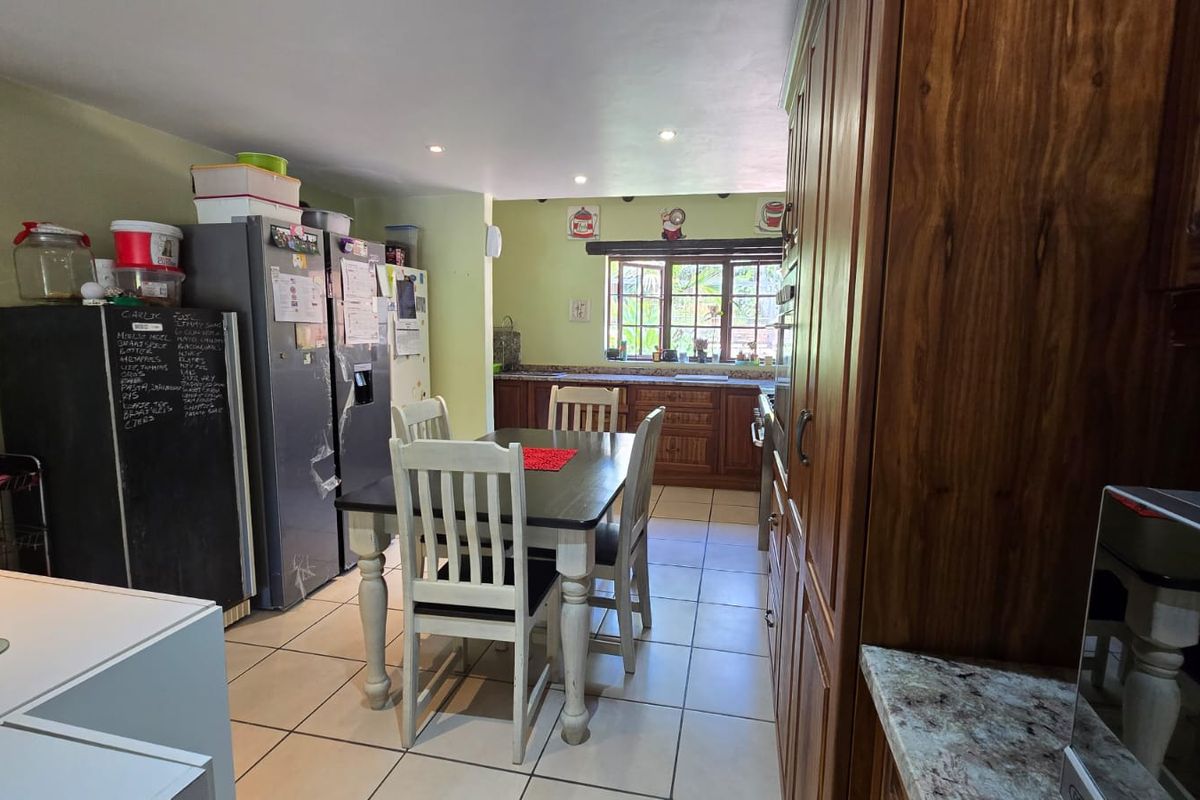 A functional kitchen featuring wooden cabinetry, tiled flooring, and a dining area, offering a traditional layout with ample storage and natural light.