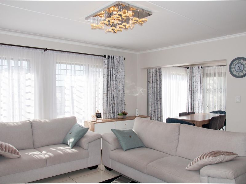 A bright and well-maintained open-plan living and dining area featuring tiled flooring and a decorative ceiling light fixture.