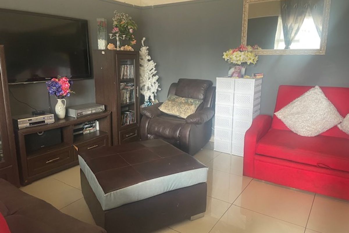 A living room featuring tiled flooring and coved ceilings, currently showing signs of wear including peeling paint on the upper wall sections.