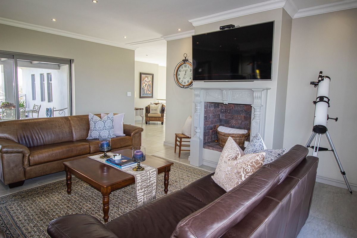 Spacious living room featuring a decorative fireplace, recessed lighting, crown molding, and large sliding glass doors leading to an outdoor patio area.