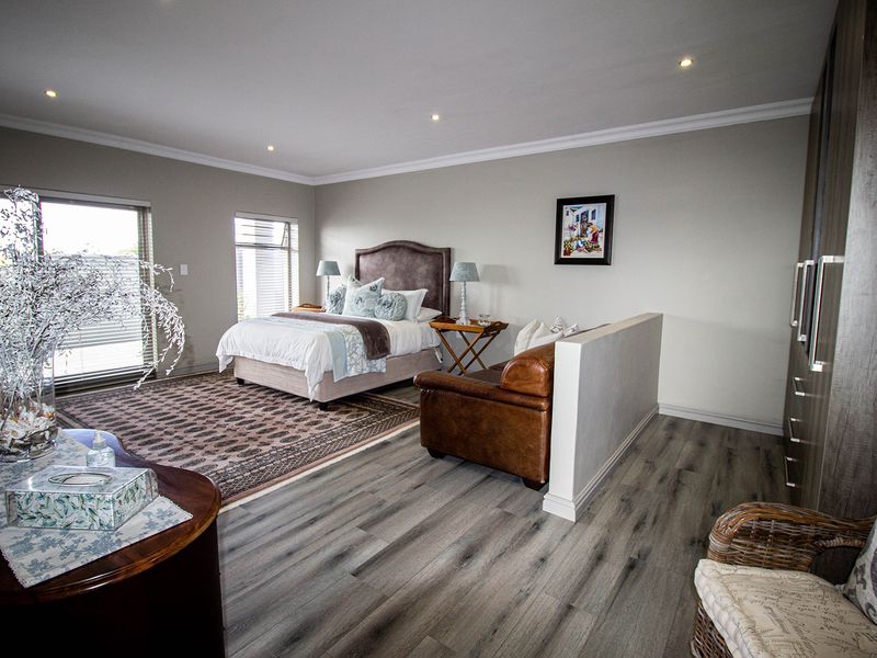 Spacious bedroom featuring modern laminate flooring, recessed downlights, built-in cupboards, and a sliding glass door providing natural light.