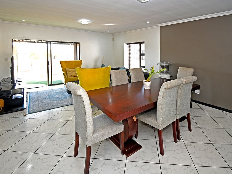 Spacious open-plan living and dining area featuring tiled floors, a stone accent wall, and large sliding doors providing access to the outdoor space.