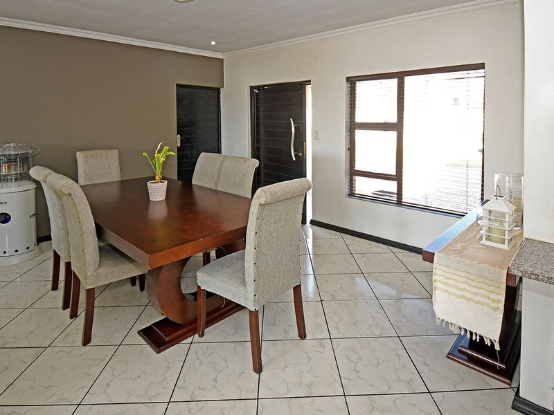 A dining area featuring tiled flooring, coved ceilings, and natural light through an aluminium-framed window, providing a functional space for family meals.