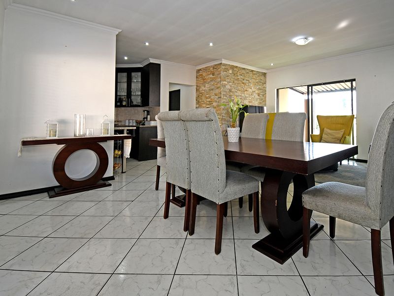 Spacious open-plan living and dining area featuring tiled floors, a stone feature wall, and seamless access to the outdoor patio through sliding glass doors.