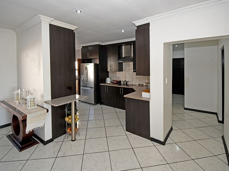 Modern kitchen featuring dark wood cabinetry, granite countertops, stainless steel appliances, tiled flooring, and a decorative stone feature wall.