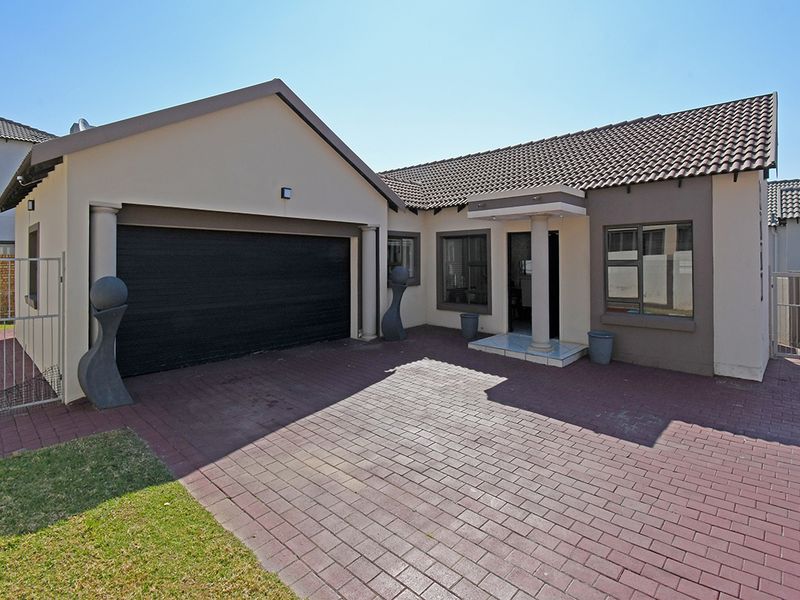 Front elevation of a residential property featuring a paved driveway, double garage, and a covered entrance with a tiled roof.