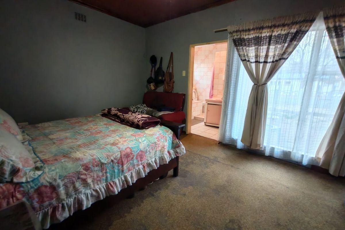 A bedroom featuring a timber ceiling, sliding glass door access to the exterior, and an attached en-suite bathroom.