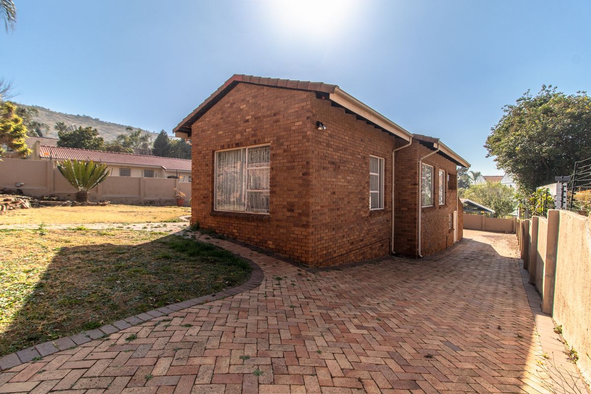 A detached brick-faced dwelling featuring a paved driveway and surrounding garden area, showcasing a traditional exterior design.