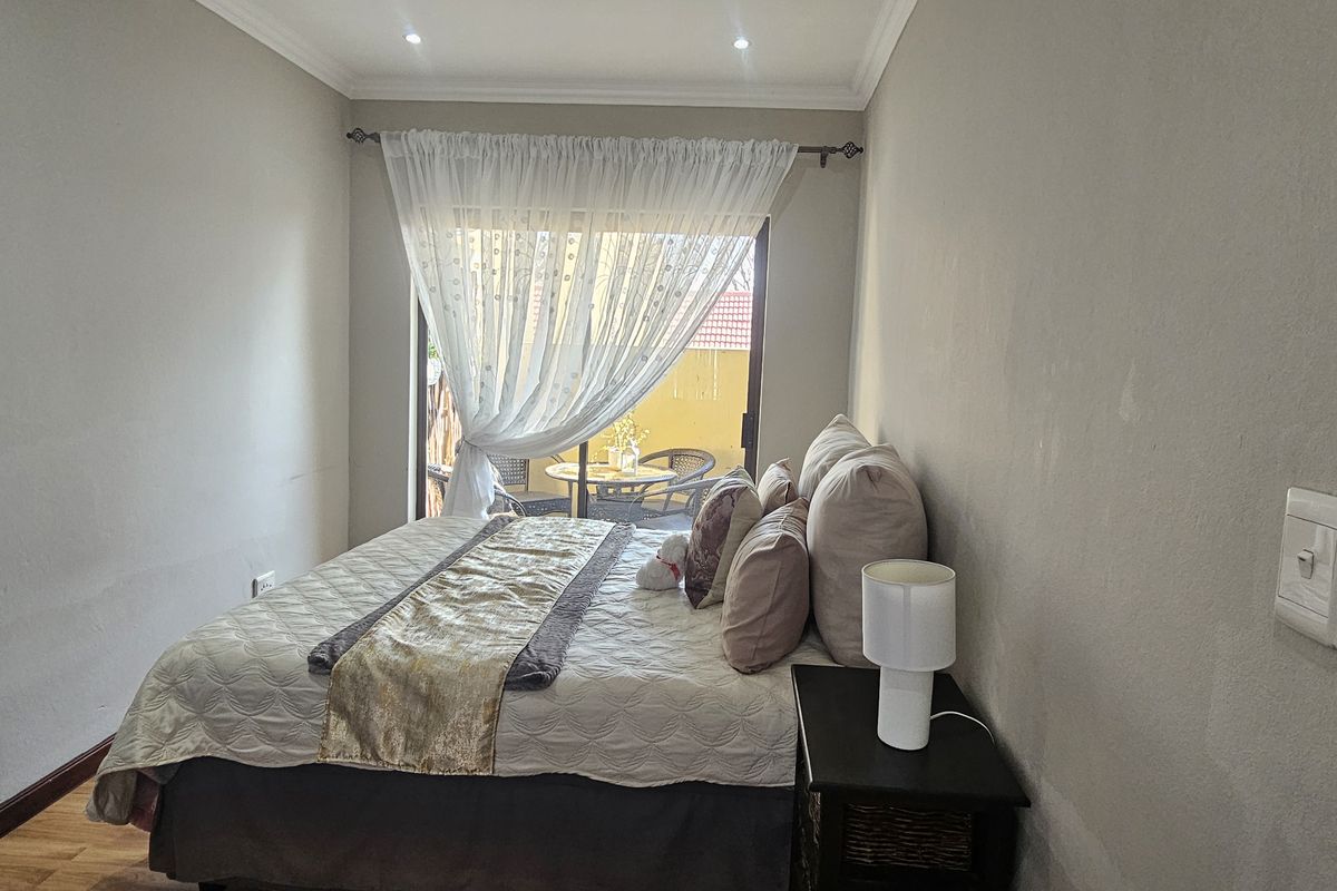 A well-lit bedroom featuring laminate flooring and a sliding glass door that provides direct access to an outdoor patio area.