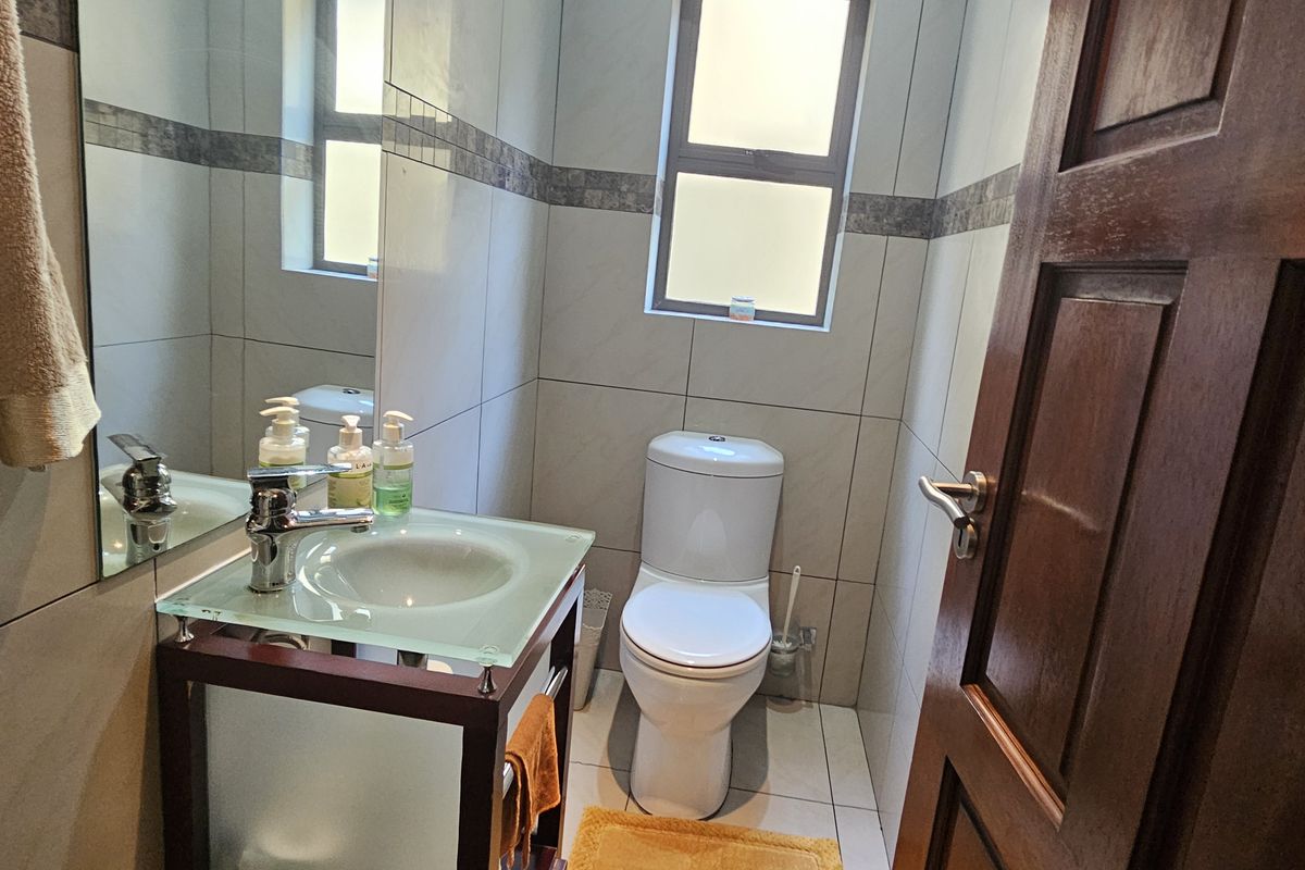 A compact, well-maintained bathroom featuring a modern glass vanity basin, tiled walls, and a functional toilet.