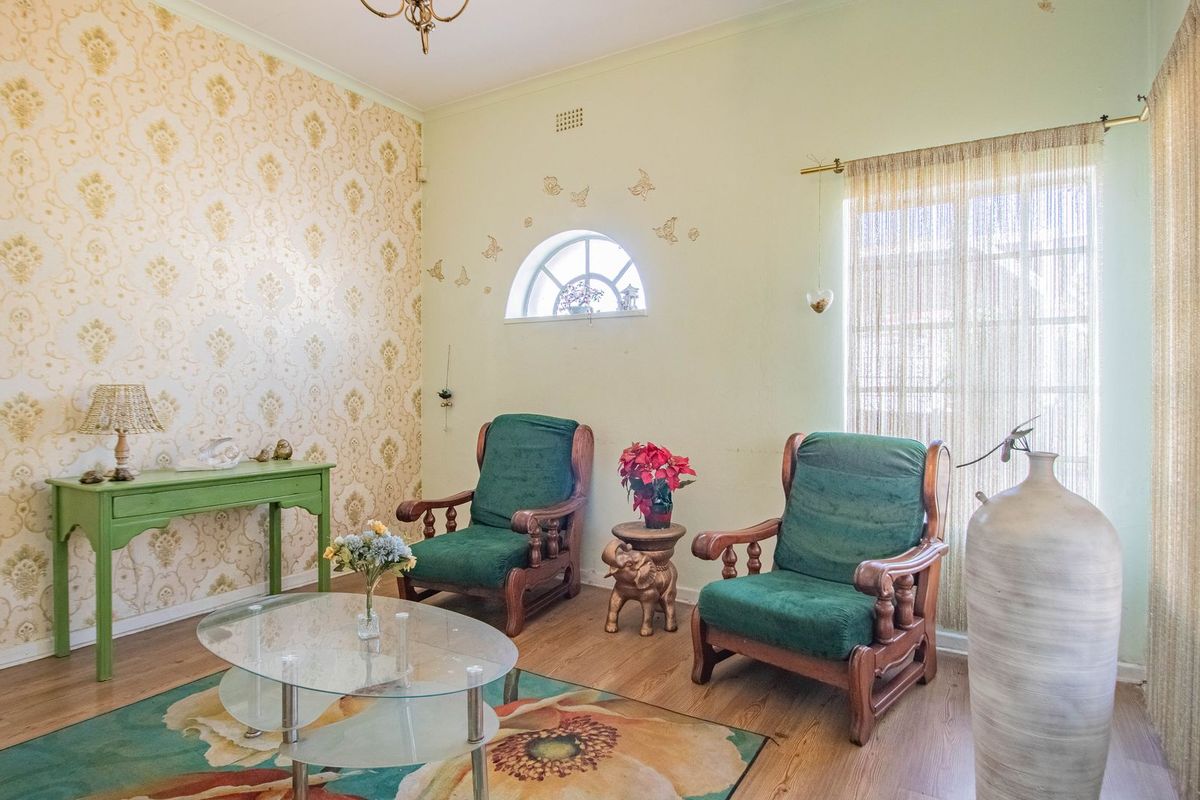 A cozy living room featuring laminate flooring, a decorative arch window, and patterned wallpaper, offering a warm and inviting atmosphere.