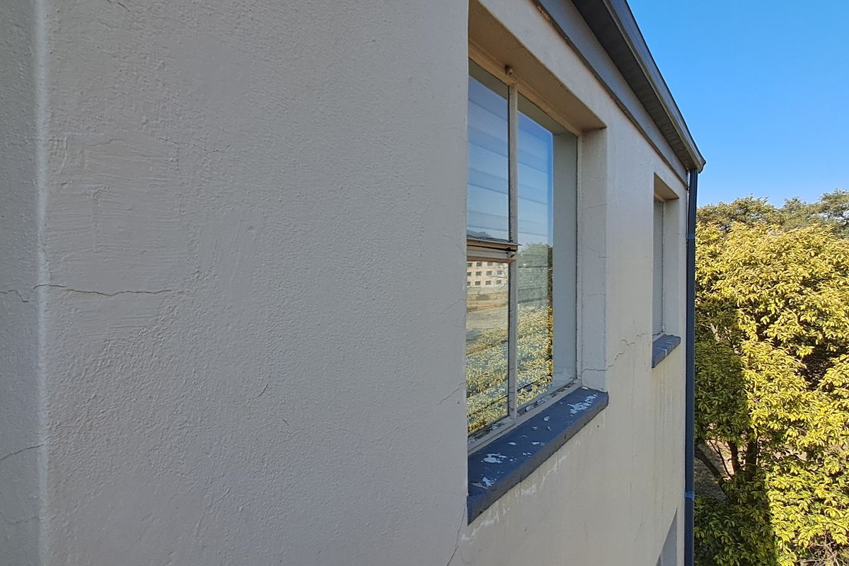 Exterior view of the building facade showing visible plaster cracking and weathered window sill paint.
