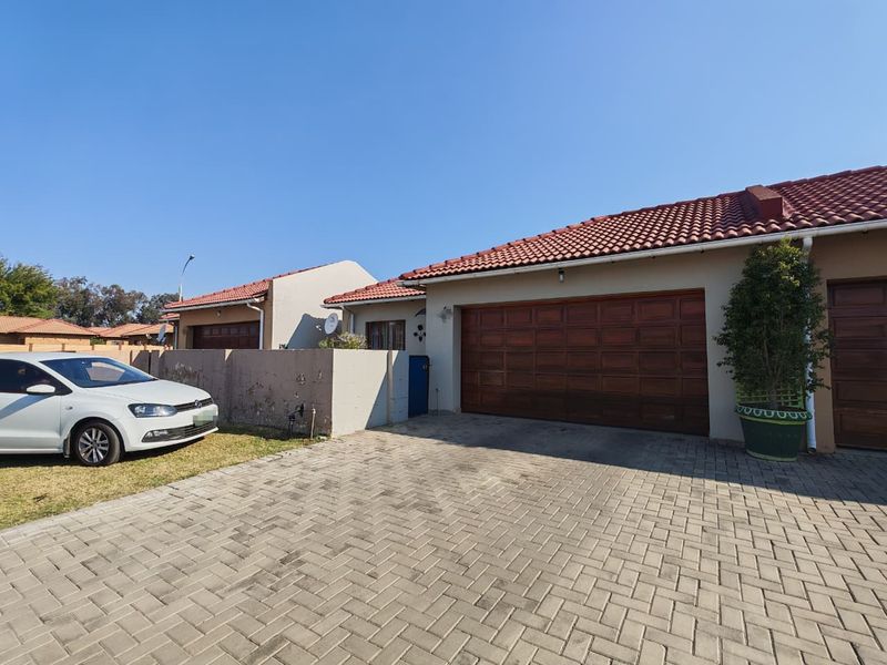 Front exterior view of the property featuring a paved driveway, a wooden garage door, and a tiled roof.