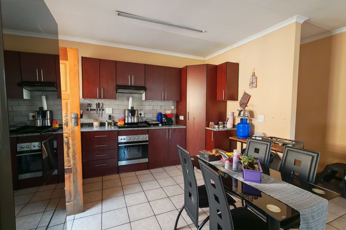 A functional kitchen featuring dark wood cabinetry, built-in oven and hob, tiled backsplash, and tiled flooring, providing a practical workspace.