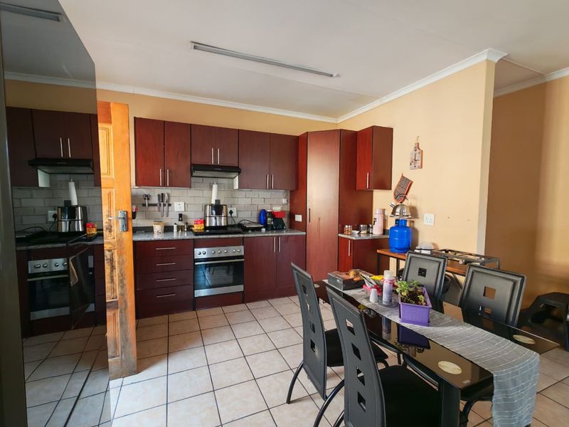 A functional kitchen featuring dark wood cabinetry, built-in oven and hob, tiled backsplash, and tiled flooring, providing a practical workspace.