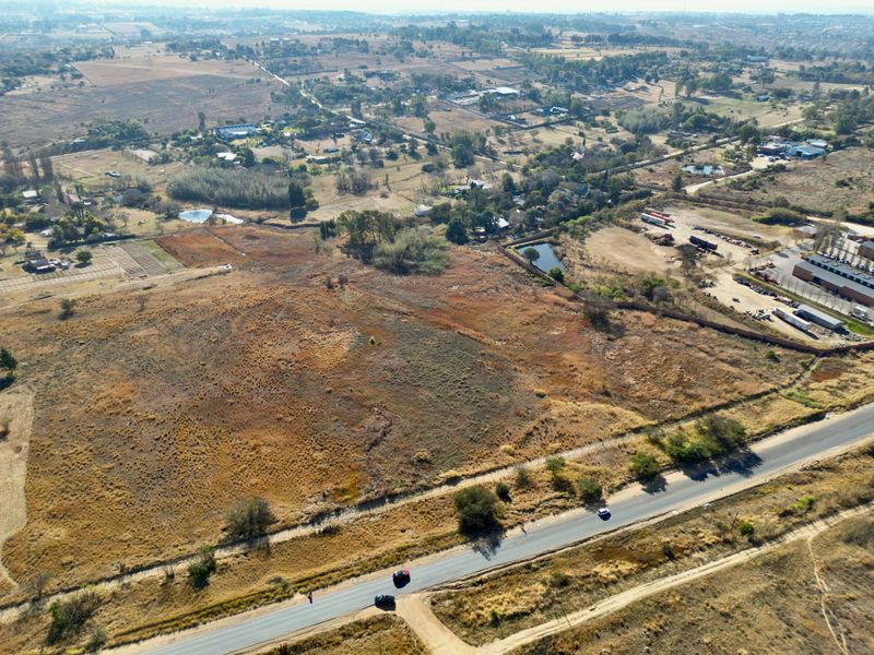 An aerial view of a large, undeveloped residential plot of land with direct road access, situated in a semi-rural area.