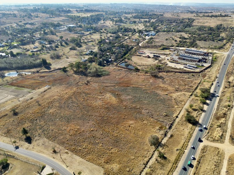 Aerial view of a large, undeveloped residential vacant land plot with direct road access and surrounding rural landscape.
