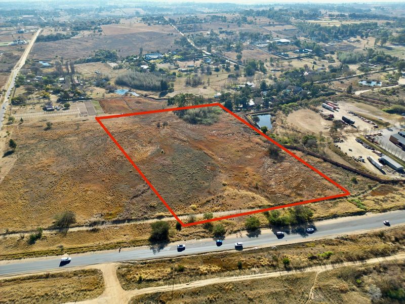 Aerial view of a large, vacant residential plot of land with clear boundary markings, situated in a semi-rural area.
