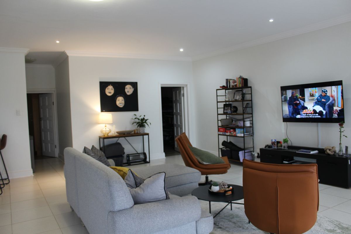 A spacious living room featuring neutral walls, tiled flooring, recessed downlighting, and coved ceiling details, providing a comfortable and well-maintained living area.